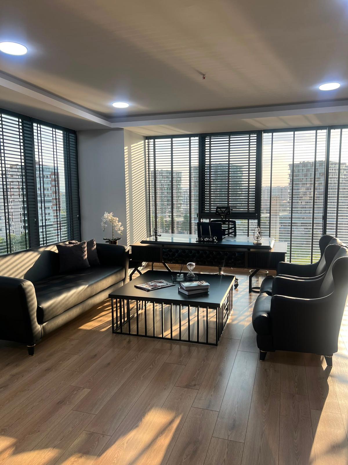 Salonun görüşme alanı, panjurlardan gelen gün ışığıyla
